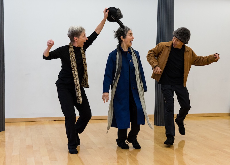 Three older performers wearing out wear and smile at one another